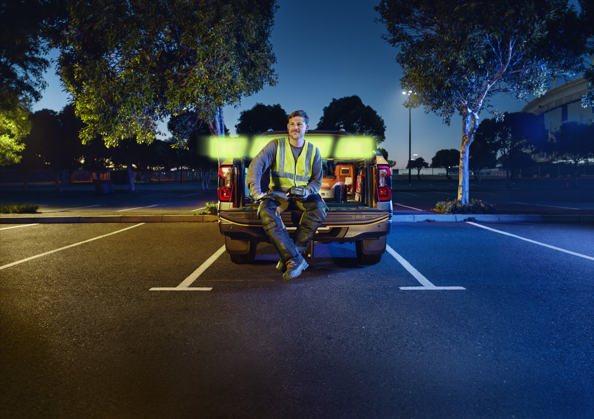 Pro landscaper sitting on the loading bed of a pickup and holding an ALLPRO STIHL AP 300.0 P C